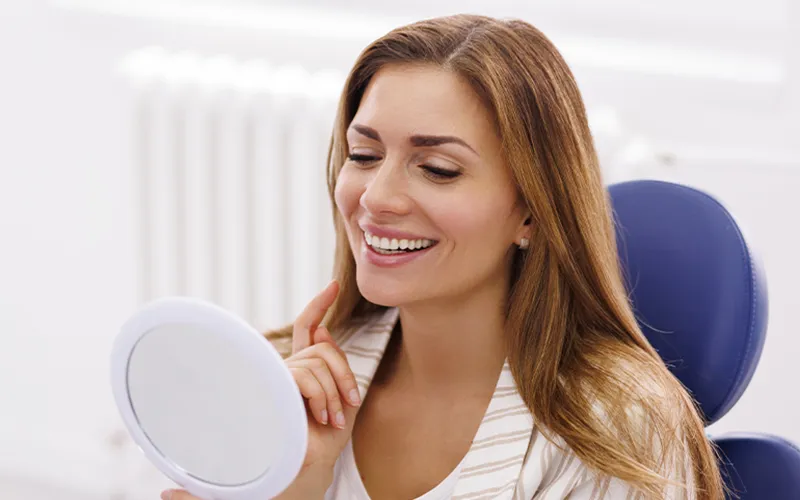 female with veneers looking at the mirror